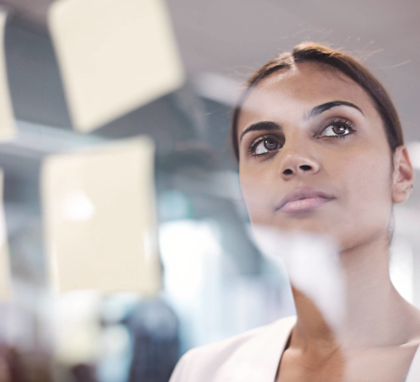 A woman thinks in front of a transparent board