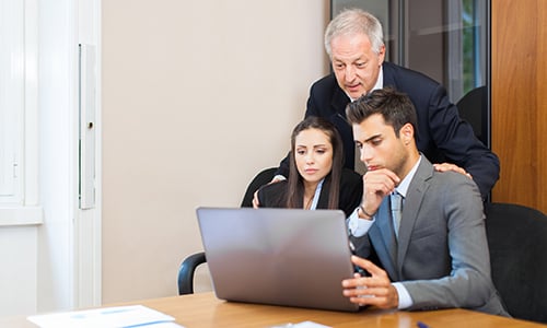 An old businessman who supports two young entrepreneurs in front of a laptop