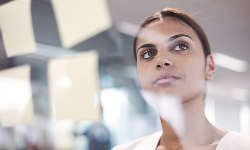 A woman thinks in front of a transparent board