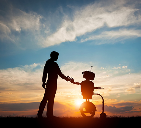 A man and a robot shake hands at sunset