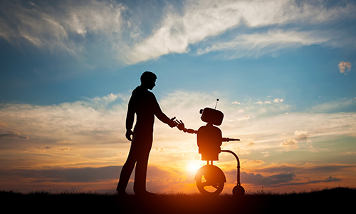 A man and a robot shake hands at sunset